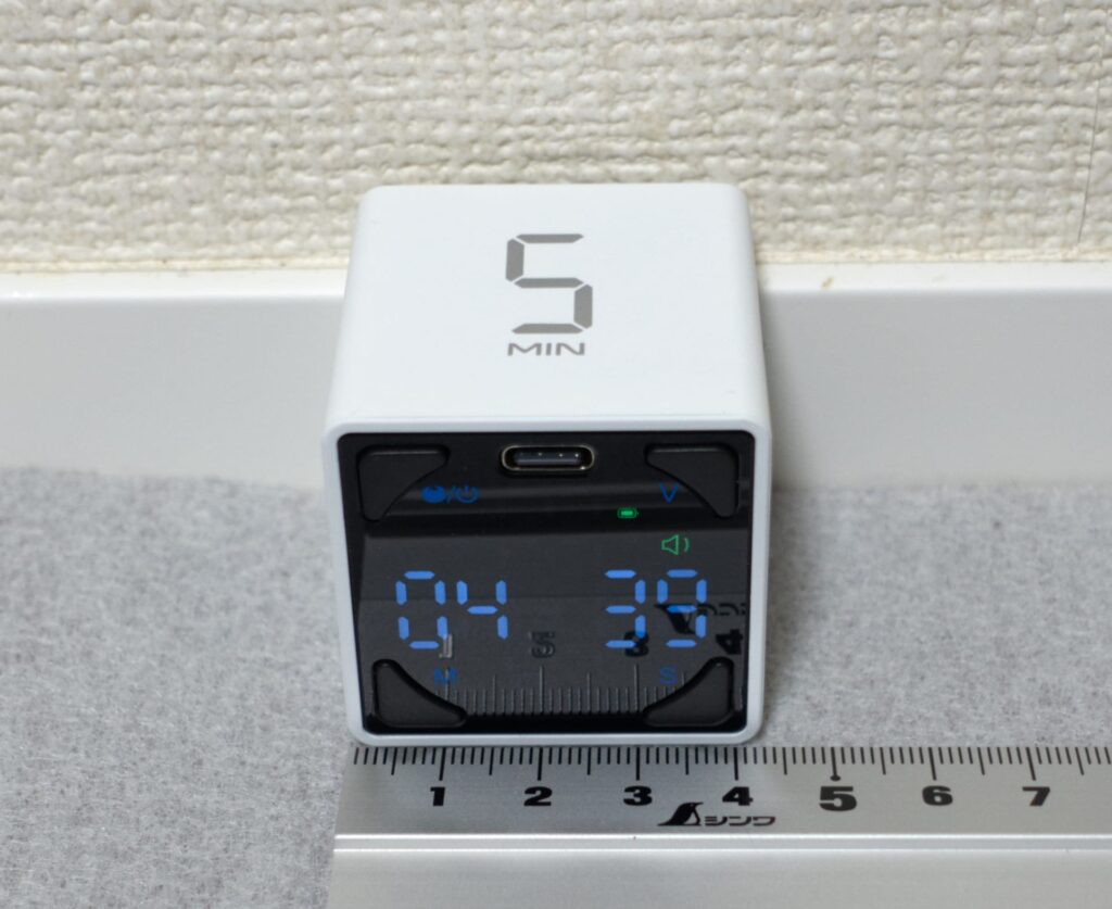 TickTimer Cube T4を正面から撮影し、定規と並べてサイズを確認している写真